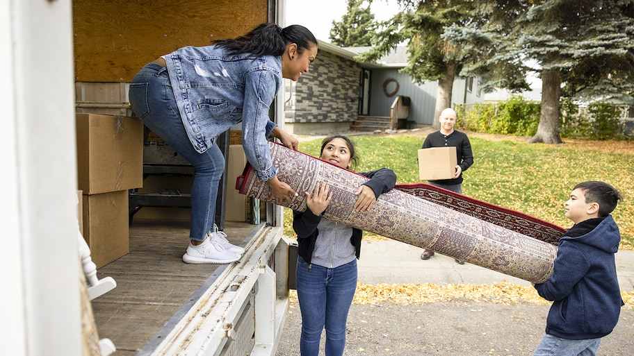 woman and her family putting rug in moving truck